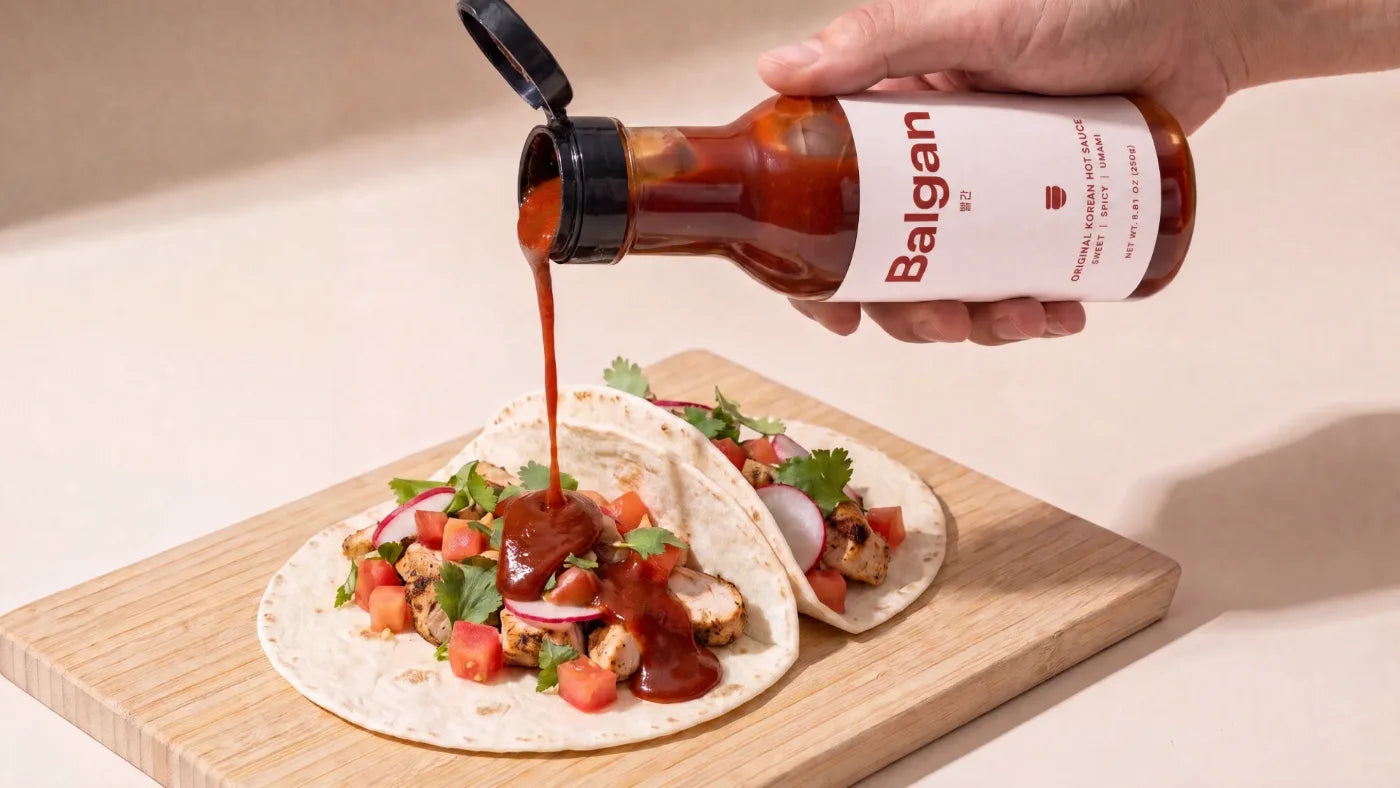Pouring Balgan Korean hot sauce over chicken tacos