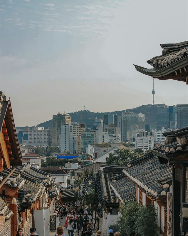 Tiled hanok rooftops of Bukchon village with the Seoul skyline behind
