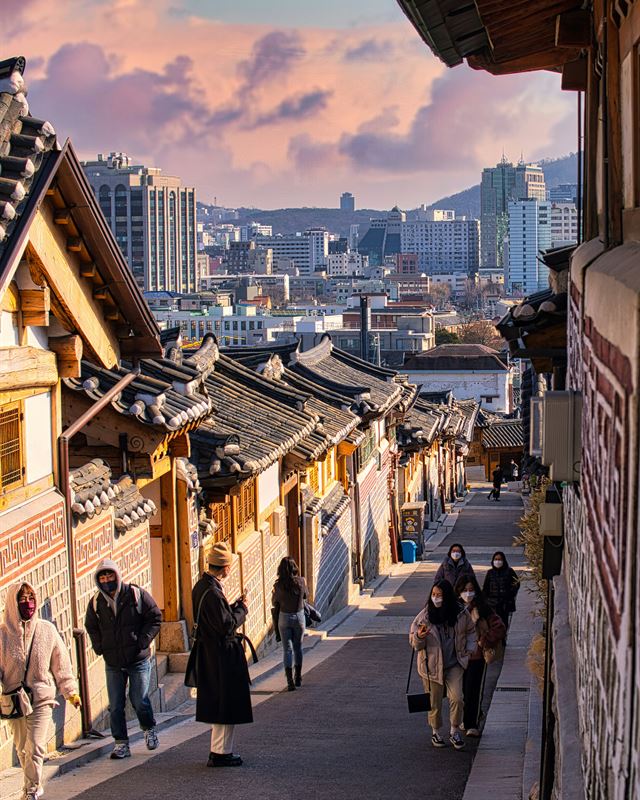 Hanok alley in Seoul at sunset with people walking