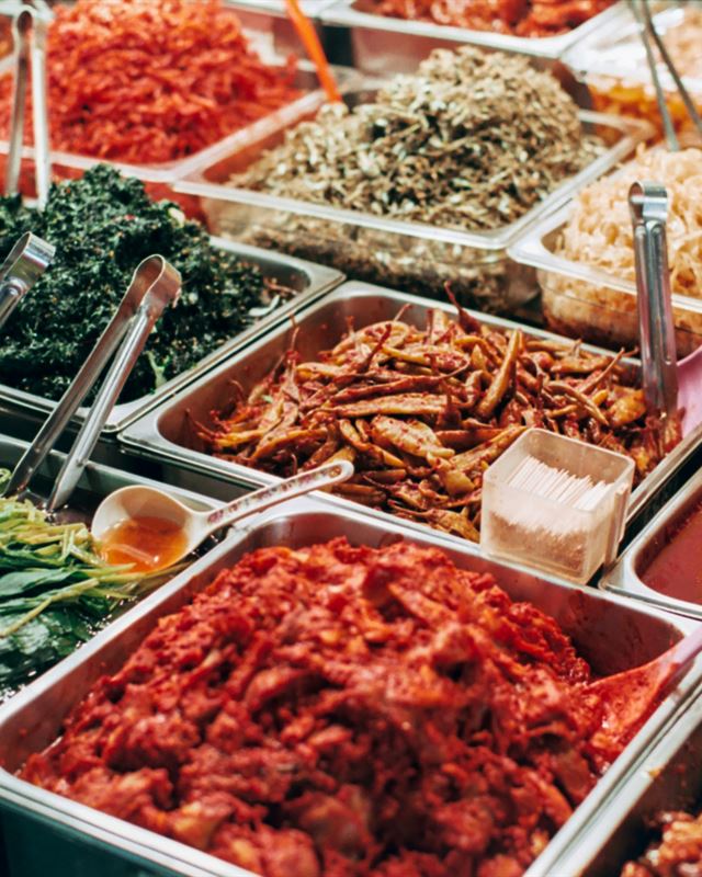 Trays of kimchi and seasoned banchan at a Korean market