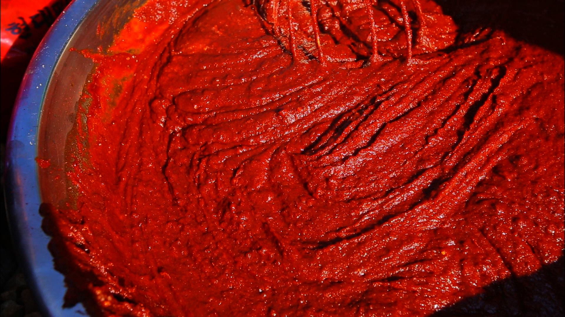 Fermented gochujang paste being stirred in a large vessel