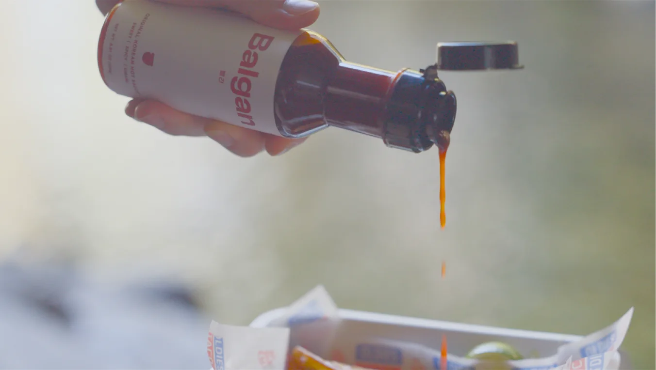 Balgan Korean hot sauce being poured from the bottle over a takeout box